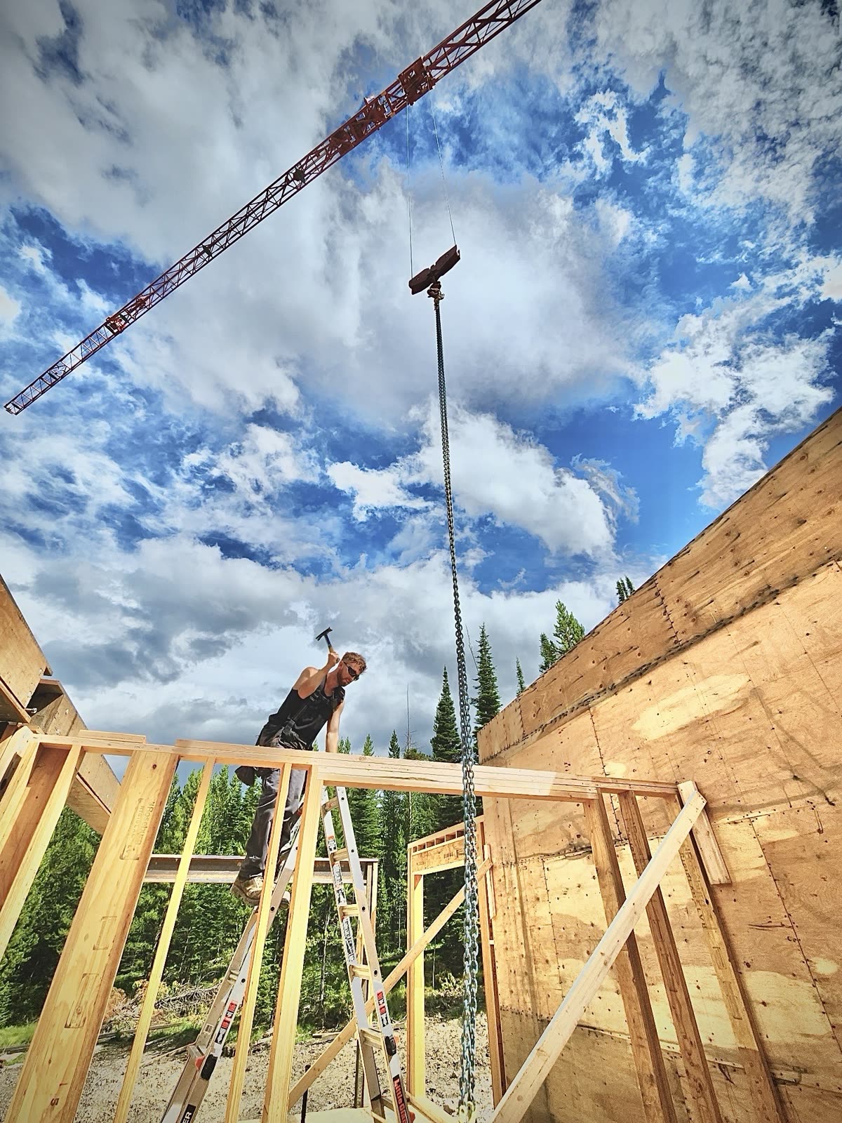 Jeb Black nailing off a top plate on a framed wall under a crane